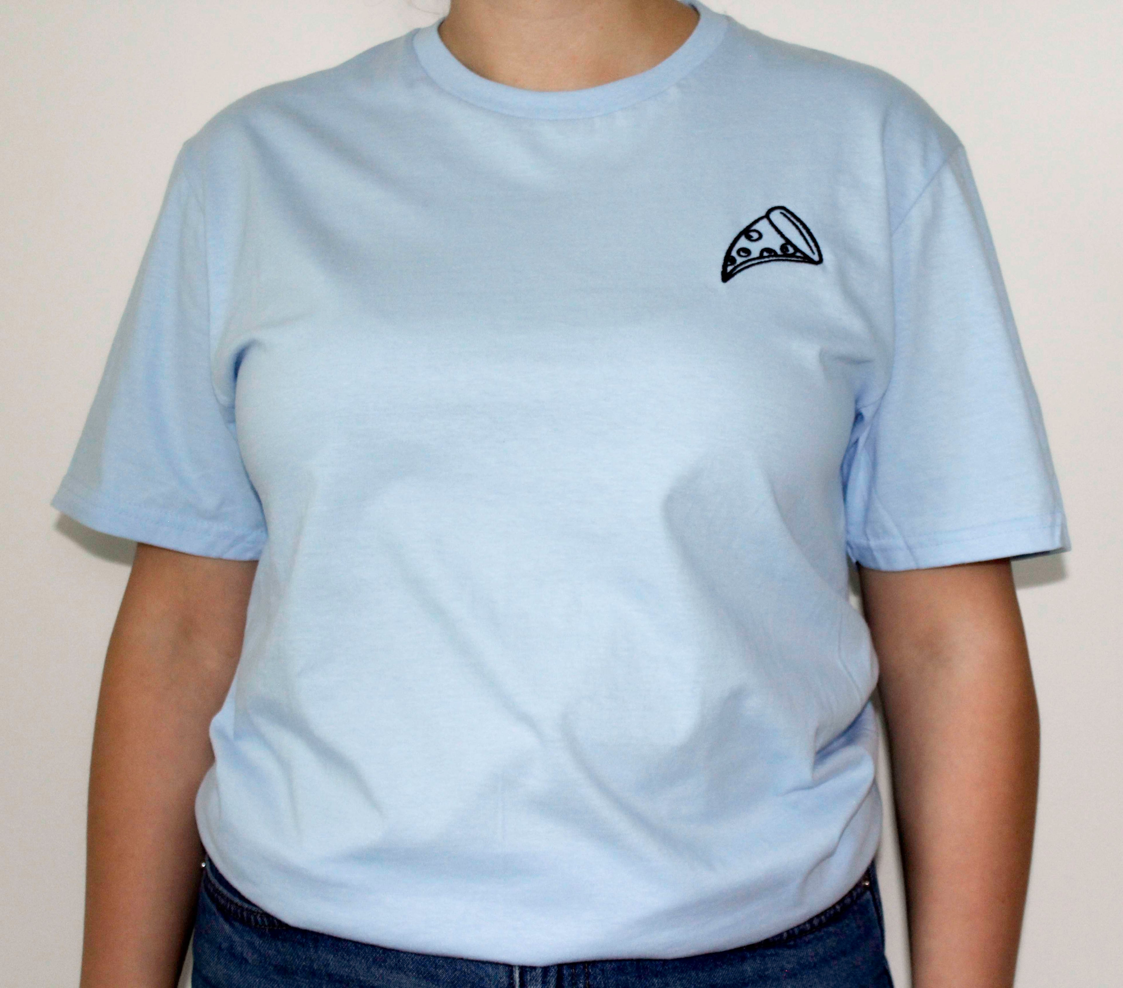 White t-shirt with a small pizza embroidery on the chest worn by a person against a plain background