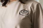 Beige t-shirt with a black cinnamon bun embroidery on the chest